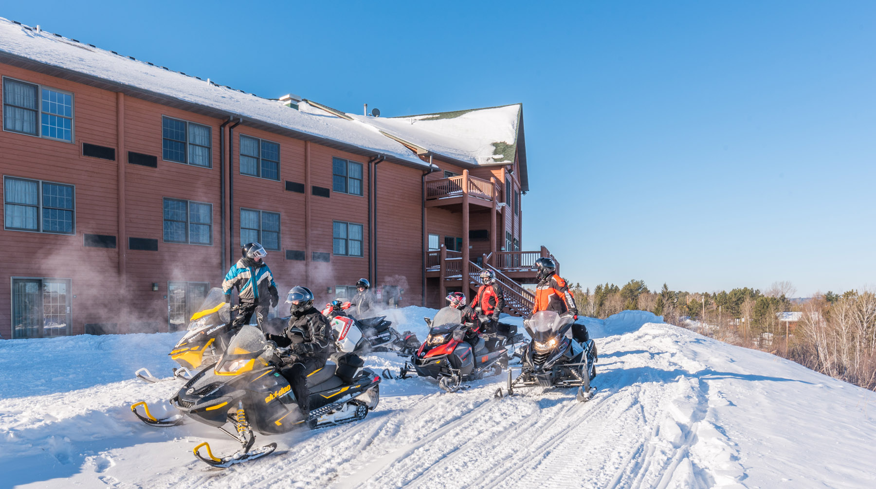 Several people on snowmobiles outside of Grand Ely Lodge